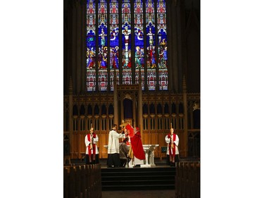 Roman Catholic Cardinal Thomas Colllins performs the Veneration of the Cross with the help of a priest during  Good Friday mass at St. Michael's Cathedral Basilica on Bond St. To and empty church on Good Friday on Friday April 10, 2020. Jack Boland/Toronto Sun/Postmedia Network