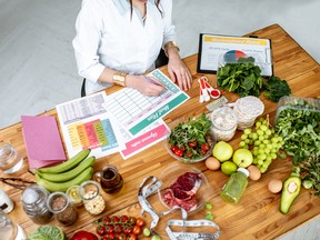 Dietitian writing a diet plan, view from above on the table with different healthy products and drawings on the topic of healthy eating