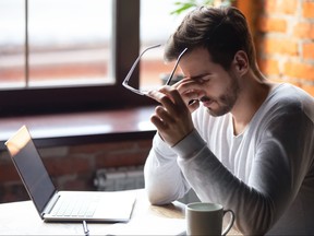 Upset man massaging nose bridge, taking off glasses, feeling eye strain