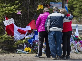 A family pays their respects to victims of the mass killing at a checkpoint in Portapique, Nova Scotia on Friday, April 24, 2020.