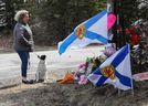 Denise Caume und ihr Hund Mimi sind vor dem provisorischen Denkmal zu sehen, das am 23. April 2020 in Portapique, Nova Scotia, in Erinnerung an eine Massenerschießung errichtet wurde.