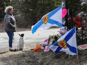 Denise Caume and her dog, Mimi, are seen in front of the makeshift memorial, made in the memory of Sunday’s mass shooting in Portapique, Nova Scotia on April 23, 2020.