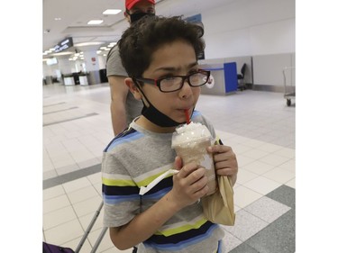 Ken Abbasi, and his 10-year old son Ibrahim of Edmonton flew 14 hours from Lahore Pakistan with help from the Canadian High Commission to Toronto. The flight cost $7,600 and he had to borrow money to get home. After a month away from Canada his son couldn't wait to drink his Tim Hortons Creamy Maple Pecan chill drink and finally pulled off his mask  Thursday April 2, 2020. Jack Boland/Toronto Sun/Postmedia Network