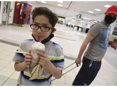Ken Abbasi, and his 10-year old son Ibrahim of Edmonton flew 14 hours from Lahore Pakistan with help from the Canadian High Commission to Toronto. The flight cost $7,600 and he had to borrow money to get home. After a month away from Canada his son couldn't wait to drink his Tim Hortons Creamy Maple Pecan chill drink and finally pulled off his mask  Thursday April 2, 2020. Jack Boland/Toronto Sun/Postmedia Network