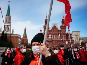 Russian Communist party members and supporters walk towards the Mausoleum of the Soviet state founder and revolutionary leader Vladimir Ilyich Ulyanov aka Lenin to hold a flower-laying ceremony marking the 150th anniversary of his birth on Red Square in Moscow on April 22, 2020, during a strict lockdown in Russia to stop the spread of COVID-19.