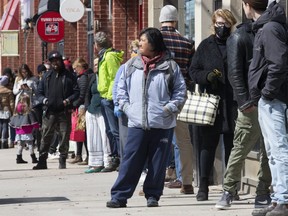 Patrons line up outside of a store along Queen. St. E. in the Beaches on Saturday April 11, 2020.
