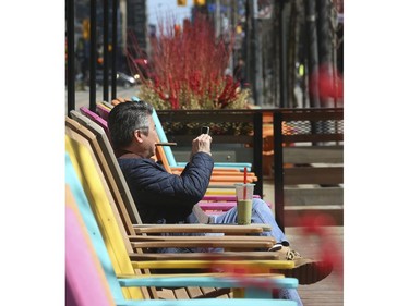 Enjoying a coffee, smoking a Cuban cigar and taking in some sunshine along King St. W. In front of Metro Hall's David Pecaut Square in Wednesday April 1, 2020. Jack Boland/Toronto Sun/Postmedia Network