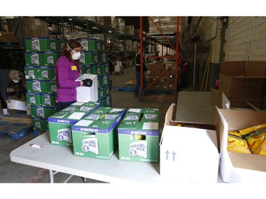 Volunteers of the Toronto Daily Bread Food Bank sorts through a box of supplies at their location on  New Toronto St. in Etobicoke. The TDBFB has set up an inflatable medical tent outside its facility along with a conveyor belt to get food to its clients since they cannot come in the building  on Wednesday April 8, 2020. Jack Boland/Toronto Sun/Postmedia Network