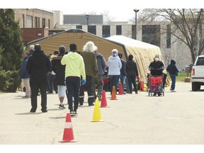 The line-up leading towards the Toronto Daily Bread Food Bank on New Toronto St. in Etobicoke. The TDBFB has set up an inflatable medical tent outside its facility along with a conveyor belt to get food to its clients since they cannot come in the building  on Wednesday April 8, 2020.
