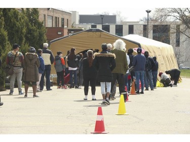 The line-up leading towards the Toronto Daily Bread Food Bank on New Toronto St. in Etobicoke. The TDBFB has set up an inflatable medical tent outside its facility along with a conveyor belt to get food to its clients since they cannot come in the building  on Wednesday April 8, 2020. Jack Boland/Toronto Sun/Postmedia Network