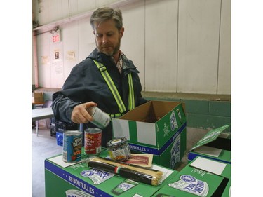 Neil Hetherington CEO of the Toronto Daily Bread Food Bank sorts through a box of supplies at their location on  New Toronto St. in Etobicoke. The TDBFB has set up an inflatable medical tent outside its facility along with a conveyor belt to get food to its clients since they cannot come in the building  on Wednesday April 8, 2020. Jack Boland/Toronto Sun/Postmedia Network