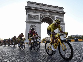 In this file photo taken on July 28, 2019 Colombia's Egan Bernal and cyclists ride down the Champs Elysees aenue next to the Arc de Triomphe in Paris.