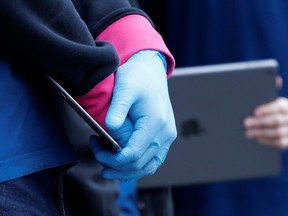 An employee holds an iPad outside an Apple Store which is closed during the global outbreak of coronavirus (COVID-19) in Pasadena, California, U.S., March 14, 2020. REUTERS/Mario Anzuoni ORG XMIT: PPP-MA622