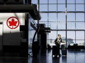 A passenger wheels her luggage near an Air Canada logo at Toronto Pearson International Airport on April 1, 2020. (Photo by Cole Burston/Getty Images)