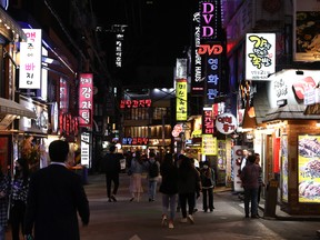 People wear masks walk along the Yeongdeungpo entertainment district on May 11, 2020 in Seoul, South Korea. The number of new coronavirus infections connected to bars and clubs in Seoul's popular nightlife district of Itaewon climbed to 94 on Monday, health authorities and local governments said amid growing concerns over a high risk of community spread.