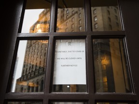 A closed sign is posted at a downtown restaurant due to the coronavirus as the reflection of the Royal York Hotel is shown in the background on Monday, March 23, 2020.