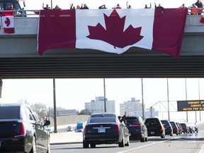 A member of the procession waves to spectators on Wednesday, May 6, 2020, as the casket of Sub-Lt. Abbigail Cowbrough passes under Avenue Road on Canada's Highway of Heroes, where a group of Canadians stand at attention to honour Cowbrough and five other members of the Canadian Armed Forces who were killed last week off the coast of Greece.