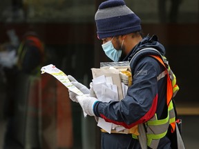 A Canada Post mail carrier delivers mail to business along Stephen Avenue Mall during the lunch hour in Calgary on Monday, May 11, 2020.