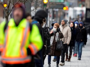A woman adjusts her mask while she waits in line as the city's public health unit holds a walk-in clinic testing for coronavirus in Montreal March 23, 2020.