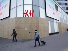 A woman wearing a protective face mask passes the closed and boarded up H&M clothing store at Eaton Centre shopping mall during the global outbreak of the coronavirus disease (COVID-19) in Toronto, Ontario, Canada April 6, 2020.