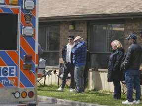 An ambulance drives by as family members look on at Pickering's Orchard Villa long-term care home on Wednesday, May 6, 2020.