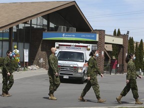 Members of the Canadian Armed Forces walk in front of Pickering's Orchard Villa long-term care home on May 6, 2020.