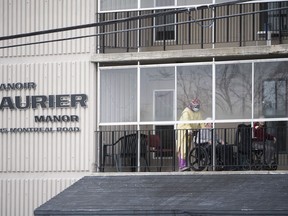 A health care worker wearing personal protective equipment (PPE) works with a resident on a balcony at the Laurier Manor in Ottawa, a long term care facility experiencing an outbreak of COVID-19, on Sunday, April 26, 2020.