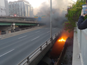 A fire burns at a homeless camp underneath the Gardiner Expressway near Spadina Ave. in Toronto on May 20, 2020.