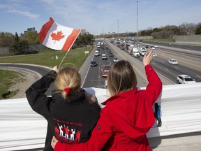 Valerie McGrady gets a hug from her daughter, Shannon, as they acknowledge appreciative motorists from below along the Highway of Heroes on Wednesday, May 6, 2020. McGrady lost her son, Cpl. Matthew McCully, in Afghanistan in 2007.