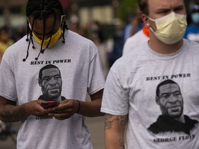 Two men wear shirts stating "Rest in Power George Floyd" outside the Third Police Precinct on May 27, 2020, in Minneapolis, Minn.