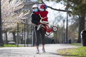 May Fuentes carries her son Victor, 4, away from the fenced off cherry blossoms at Trinity Bellwoods Park on Thursday, May 7, 2020.