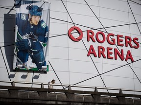 A woman walks past a large photo of Vancouver Canucks captain Bo Horvat outside Rogers Arena, home to the NHL team, in Vancouver, March 12, 2020.