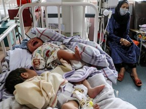 A woman sits next to newborn babies who lost their mothers following a suicide attack in a maternity hospital, in Kabul on May 13, 2020.