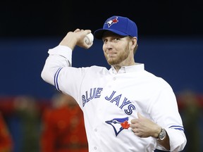 Late Toronto Blue Jays star Roy Halladay throws out a first pitch in 2014. In a new book, Halladay's widow explains why Halladay finally requested a trade form the sad-sack Jays.