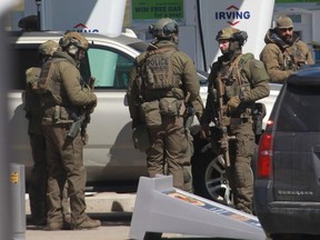 Members of the Royal Canadian Mounted Police tactical unit confer after the suspect in a deadly shooting rampage was neutralized at the Big Stop near Elmsdale, Nova Scotia on April 19, 2020.