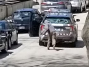 A suspect prepares to toss a rock at a Toronto police officer on Monday, May 4, 2020.