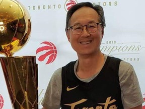 Sandy Tse, a veteran Crown prosecutor and Raptors fan, holds the Larry O'Brien Trophy championship trophy. Tse died following a battle with COVID-19 in April.