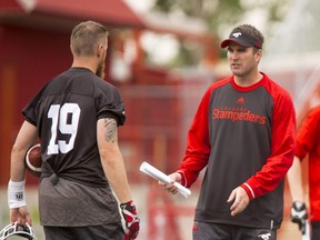 Ryan Dinwiddie, then quarterbacks coach of the Calgary Stampeders, speaks with quarterback Bo Levi Mitchell during a training camp.