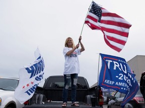 A Donald Trump supporter waves an American flag while waiting to catch a glimpse of the U.S. President after his visit to a Ford Motor Co. plant after it reopened from the coronavirus disease restrictions in Ypsilanti, Michigan, May 21, 2020.