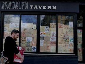A closed tavern along Queen St. E. in Toronto covers the windows with children's drawings on April 9, 2020.