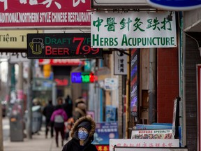 A woman, wearing a mask, walks in the Chinatown district of downtown Toronto, Jan. 28, 2020.