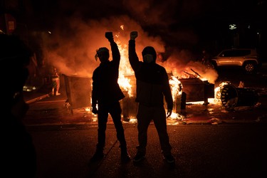 SEATTLE, WA - JUNE 08: Demonstrators raise their fists as a fire burns in the street after clashes with law enforcement near the Seattle Police Departments East Precinct shortly after midnight on June 8, 2020 in Seattle, Washington. Earlier in the evening, a suspect drove into the crowd of protesters and shot one person, which happened after a day of peaceful protests across the city. Later, police and protestors clashed violently during ongoing Black Lives Matter demonstrations following the death of George Floyd.