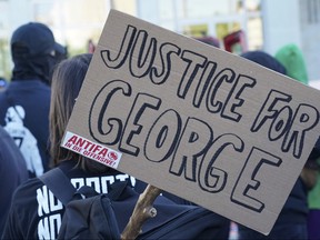 A poster with the inscription 'Justice for George' and 'Antifa on the offensive' is held by a protester during a demonstration under the motto "Youth Day - Fight for your future." George Floyd died after being restrained by Minneapolis police officers on Memorial Day May 25.