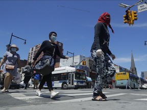 Pedestrians wear face coverings and protective masks as they cross Mains street, Monday, June 8, 2020, in the Flushing section of the Queens borough of New York.