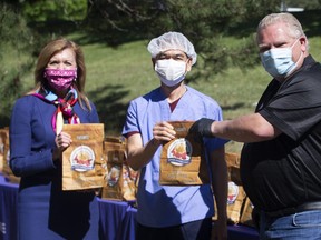 Ontario Premier Doug Ford, right, and Health Minister Christine Elliott pose for a photo with a health-care worker while handing out bagged gifts from Prince Edward Island at Birchmount Hospital, in Scarborough, Ont. on Monday, June 8, 2020.  THE CANADIAN PRESS/Chris Young