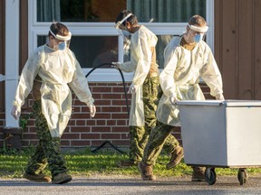 Members of the Canadian Forces assisting with COVID-19 care wash down a laundry bin in the parking lot of Altamont Care Community in Toronto on Monday, June 15, 2020.
