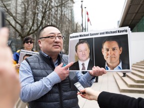 Louis Huang of Vancouver Freedom and Democracy for China holds a photo of Canadians Michael Spavor and Michael Kovrig, who are being detained by China.