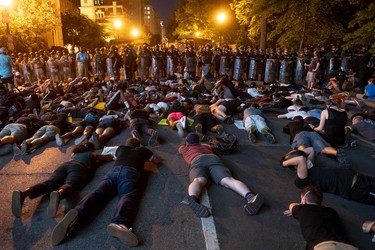 Demonstrators lay on the ground facing a police  line in front of the White House during protests over the death of George Floyd on June 3, 2020, in Washington, DC. - Former Minneapolis police officer Derek Chauvin, who kneeled on the neck of George Floyd who later died, will now be charged with second-degree murder, and his three colleagues will face charges of aiding and abetting second-degree murder, court documents revealed on June 3.