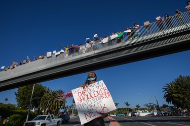 Sovereign Evans holds a sign in Newport Beach, California, on June 3, 2020 during a protest over the death of George Floyd. - US protesters welcomed new charges brought Wednesday against Minneapolis officers in the killing of African American man George Floyd -- but thousands still marched in cities across the country for a ninth straight night, chanting against racism and police brutality.