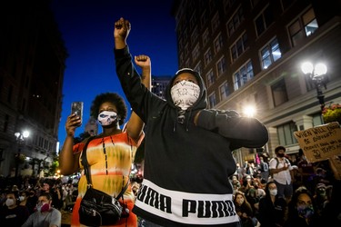 Demonstrators raise their fists during a "Sit Out the Curfew" protest against the death of George Floyd who died on May 25 in Minneapolis whilst in police custody, along a street in Oakland, California on June 3, 2020. - US protesters welcomed new charges against Minneapolis officers in the killing of African-American man George Floyd -- but thousands still marched in cities across the country for a ninth straight night, chanting against racism and police brutality.